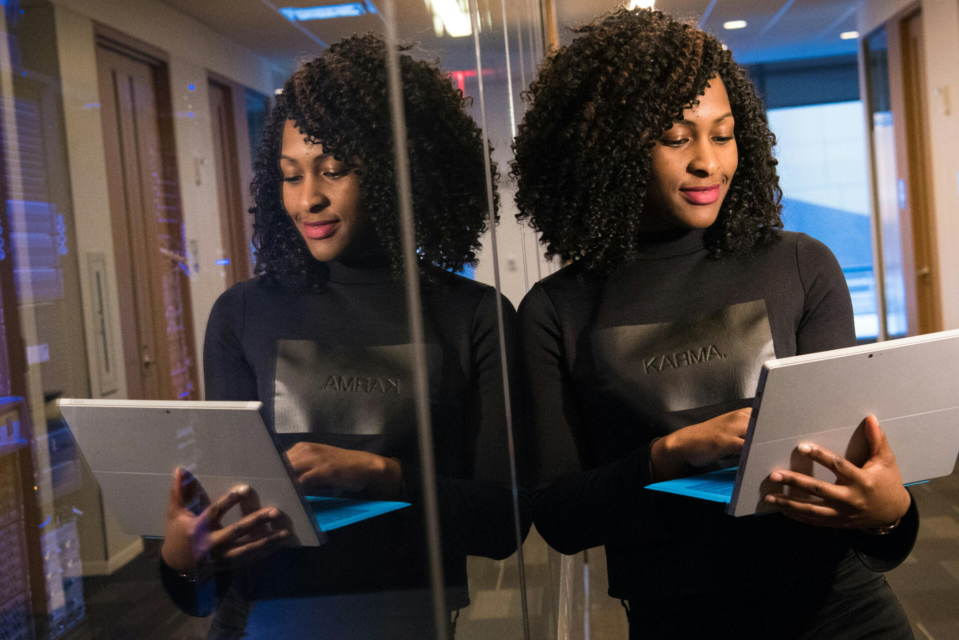 woman in mirrored coridor holding laptop